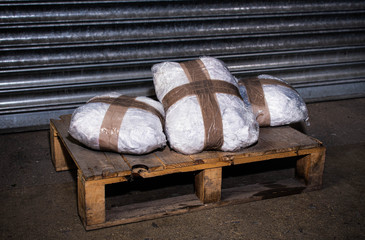 Cocaine or other illegal drug packages sitting on a pallet ready for delivery to drug dealers,...