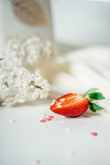Sliced strawberry, on a white cloth, near the flowers of lilac. Food photography. Advertising and commercial close up design.