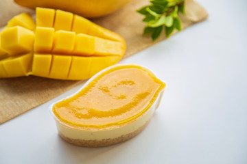 Fresh mango cheese pie on rustic table with mango fruit blurred background, pie cake made from cookie crumbs.