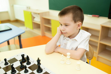 boy play chess in kindergarten