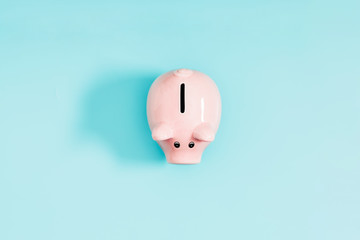 Pink piggy bank on pastel blue background. Flat lay, top view, copy space