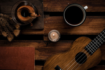 old guitar, coffee, book, candle and plant on wooden background