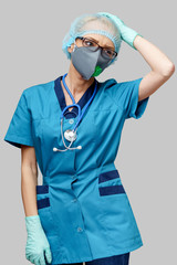 female doctor with stethoscope wearing protective mask and latex gloves over light grey background