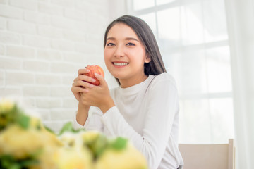 asian beauty woman holding apple. smiley face female eating apple organic fruit in house with copy space.