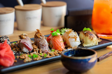 Nigiri sushi with salmon, eel, tuna and prawn, served on transparent plate. Delicious traditional Japanese food, tasty seafood, restaurant concept, food background.