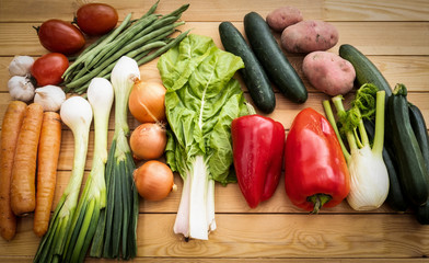 Wooden table with a large group of raw vegetables. Vegan and vegetarian lifestyles. Healthy and fresh. Recycled wood on background