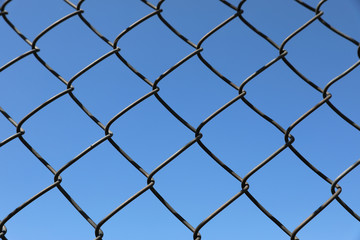 Fototapeta premium Rusted barbwire and chain link fence. Iron wire on blue sky background on a jail