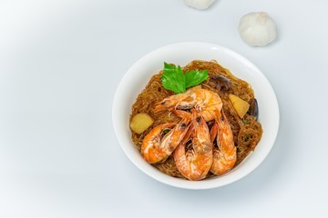 Casseroled shrimps roasted with glass noodles or prawns with Vermicelli Noodles in white blow with chinese celary on the top view. Asian Food Thai fusion style. famous food in Thailand national dish.