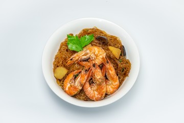 Casseroled shrimps roasted with glass noodles or prawns with Vermicelli Noodles in white blow with chinese celary on the top view. Asian Food Thai fusion style. famous food in Thailand national dish.