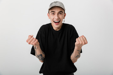 Portrait of delighted caucasian man wearing black clothes looking on camera and clenching fists