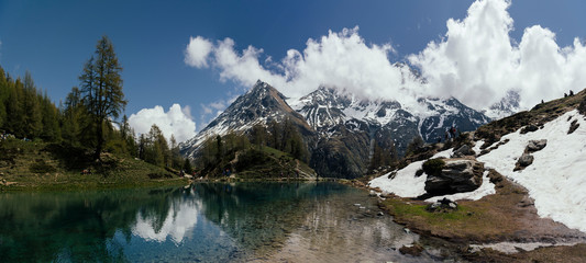 Panorama of the Alpine mountains and lake in the clouds.