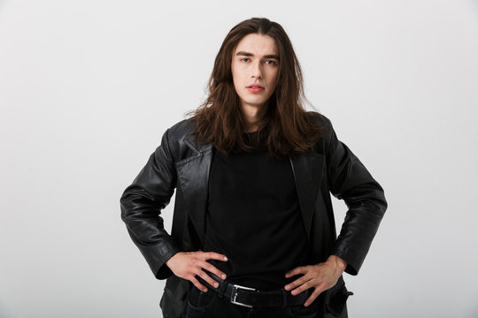 Portrait of brunette caucasian man with long hair wearing black lather jacket posing and looking at camera