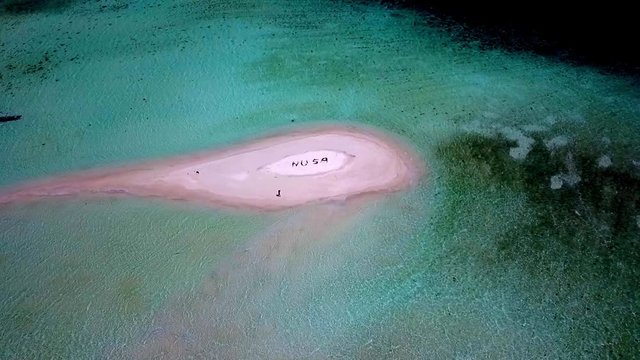 NUSA letters meaning island in Indonesian language formed by people on a tiny reef isle in Raja Ampat, Aerial dolly out shot