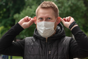 Large portrait of a light adult man with blue eyes in a medical mask