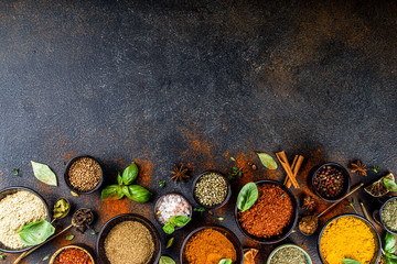 Set of Spices and herbs for cooking. Small bowls with colorful  seasonings and spices - basil, pepper, saffron, salt, paprika, turmeric. On black stone table top view copy space - obrazy, fototapety, plakaty