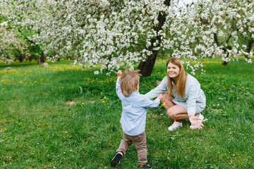 Mom and son for a walk. A child and mom are walking in the garden. Relations between mom and son.