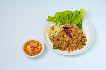 Crispy Catfish spicy Salad Served With Shredded Green Mangoes,green Cabbage, fried dried Chilies and Peanuts fried Isolated on White Background. Famous traditional food in Thailand and Asia.