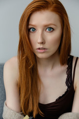 Fototapeta premium Close portrait of a blue-eyed red-haired girl looking at the camera.