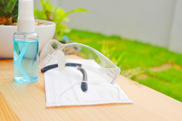 Alcohol spray portable with face mask and glasses on grass background.Hygiene, coronavirus concept. Prevent the spread of germs and bacteria and uniquely earn coronavirus using covid 19.Close up.
