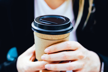 Fototapeta na wymiar Close-up hand holding a paper coffee cup to take away