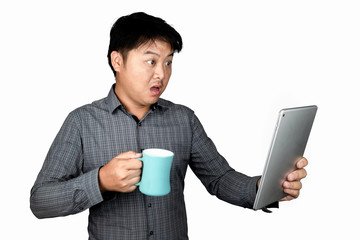 A handsome male Asian office worker standing with a glass of water Blue and the tablet looked at the tablet showing the emotion of people shocked, excited isolated on a white background