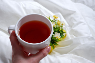 A woman's hand holds a Cup of tea. white linen. Minimalism. Comfort