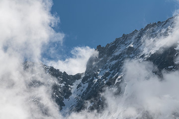 Peak of the mountains in the clouds on a background of blue sky.