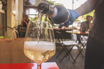 Bar tender pouring sparkling wine on a glass wearing safety gloves. Coronavirus phase 2 concept...
