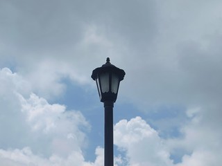 Lonely stylish street lantern on a background of cloudy sky. Old retro style. Up view from the bottom. Close up, macro, isolated, conceptual image. Beautiful clouds, gray sky. Design idea. Single lamp