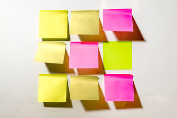 Multi-colored square post-it notes pasted on a white wall
