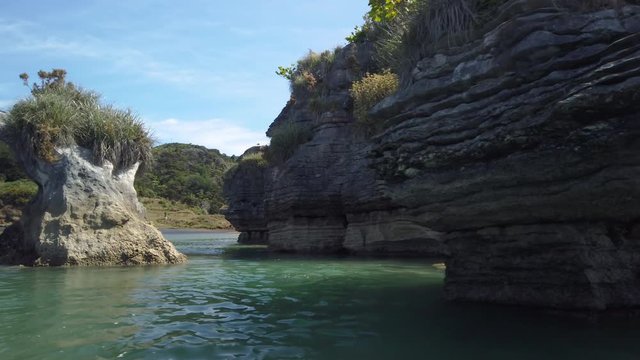 4K left to right pan hand held slide motion of the rock formations know as the Pancake Rocks on the west coastline at the town of Raglan, popular for leisure kayakers and paddleborders,New Zealand  