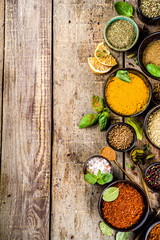 Fototapeta na wymiar Set of Spices and herbs for cooking. Small bowls with colorful seasonings and spices - basil, pepper, saffron, salt, paprika, turmeric. On rustic wooden plank table background, top view copy space