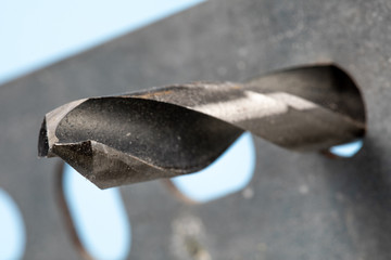 extreme close up of an electric drill with a high speed metal drill bit through a piece of metal