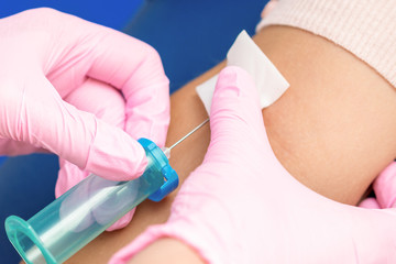 Nurse hands are introducing the coronavirus vaccine introducing a needle into a vein of arm.