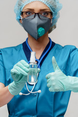 medical doctor nurse wearing protective mask - holding bottle of sanitizing spray or gel