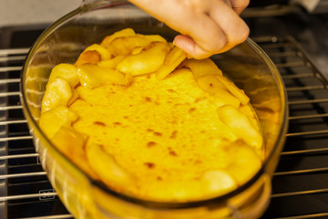 hand puts apple slices on a glass cake pan