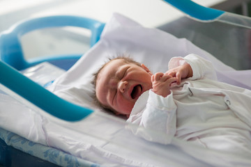 Fototapeta premium Beautiful newborn baby boy, laying in crib in prenatal hospital