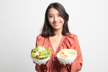 Young Asian woman with potato chips and salad .