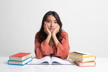 Young Asian woman read a book with books on table .