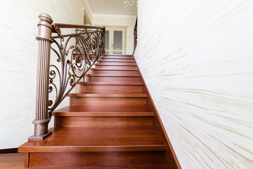Wooden stairs from elite raw materials of dark color with metal, forged railings. Handmade