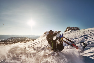 Snowbike rider in mountain valley. Modify dirt bike with snow splashes and trail. Snowmobile sport riding, winter sunny day