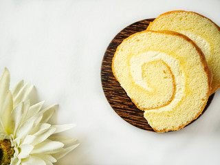 Vanila coconut cream jam roll are on the wooden plate and  decorated white flower and on isolated white background.