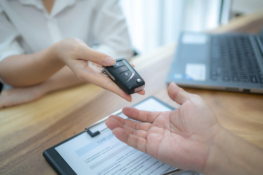 A saleswoman is handing the car keys to the customer after to make a purchase contract.