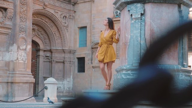 Woman walking and looking at the old buildings of the cathedral square in Murcia.