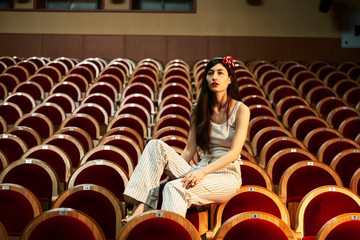 portrait of a pretty girl hipster in a movie theater wearing hat, dreaming alone, fashion lufestyle people concept