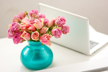 silver laptop on a table with a bouquet of roses