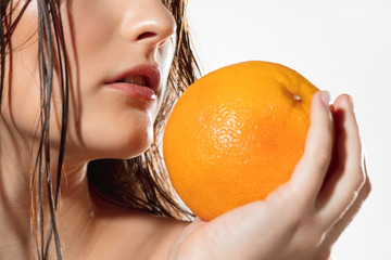 Sun in hands. Close up of beautiful young woman with big grapefruit on white background. Concept of cosmetics, makeup, natural and eco treatment, skin care. Shiny and healthy skin, fashion, healthcare