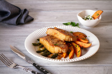Juicy broiled pork chop steaks with asparagus, sweet potatoes and yogurt sauce.  horizontal image