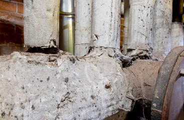 dangerous broken asbestos wrap insulation on rusty heating system pipes