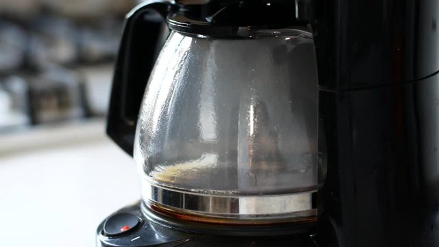 Morning coffee is brewed in a black coffee maker in the morning at dawn.
